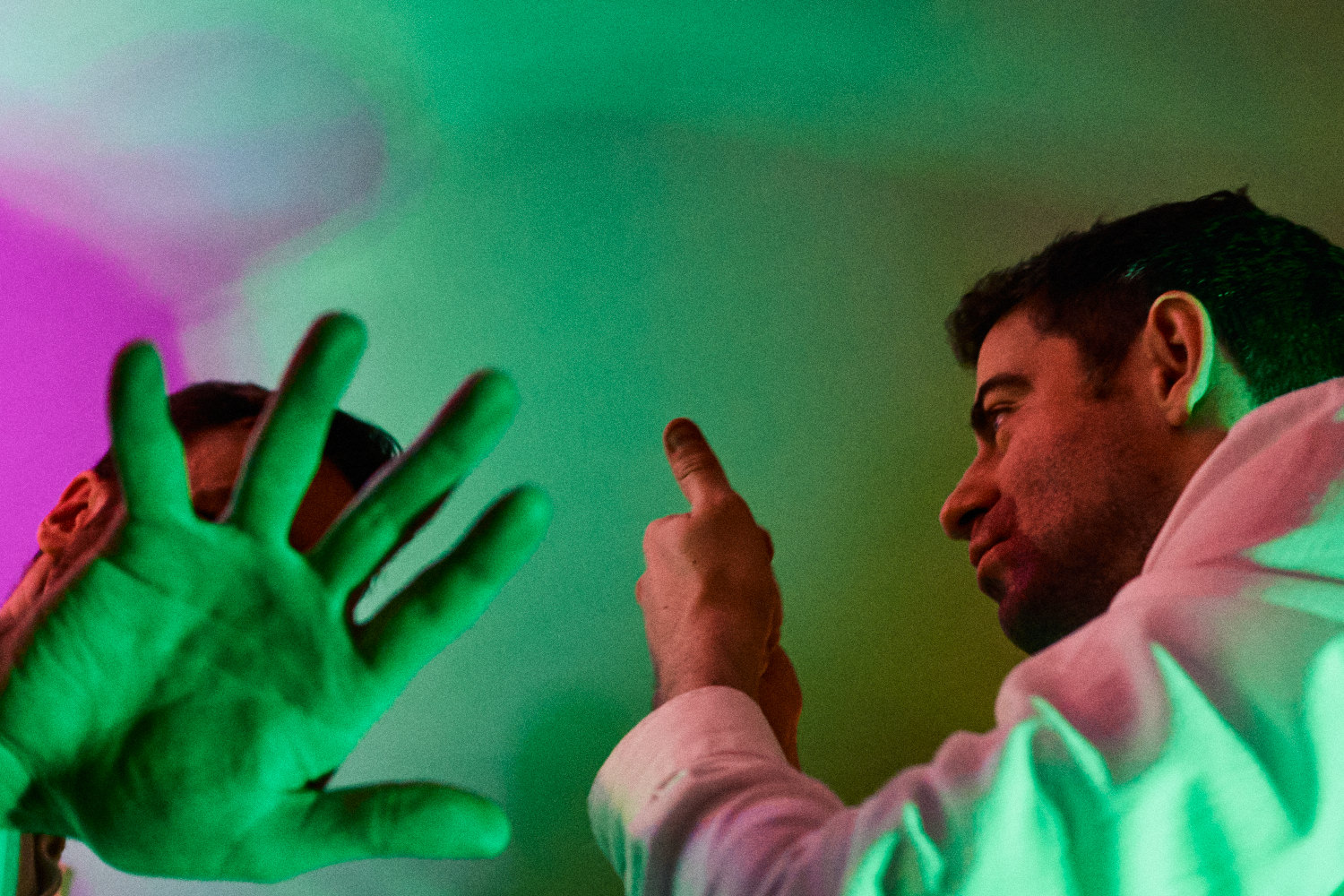 Two dancers make expressive hand gestures in green light at Medley Dublin