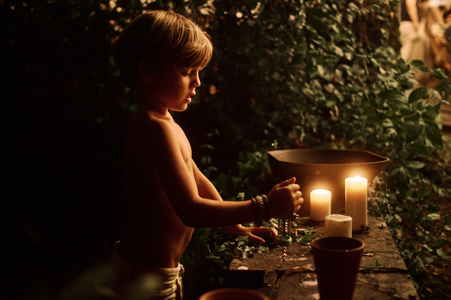 A child is illuminated by candle light at an outdoor wedding reception